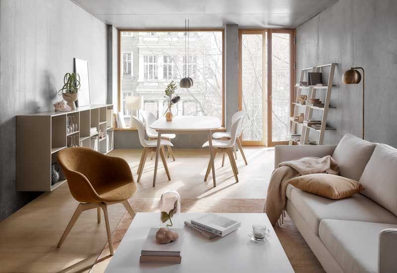 Salón comedor con mesa blanca, sillas blancas y de madera, aparador y estantería tipo escalera