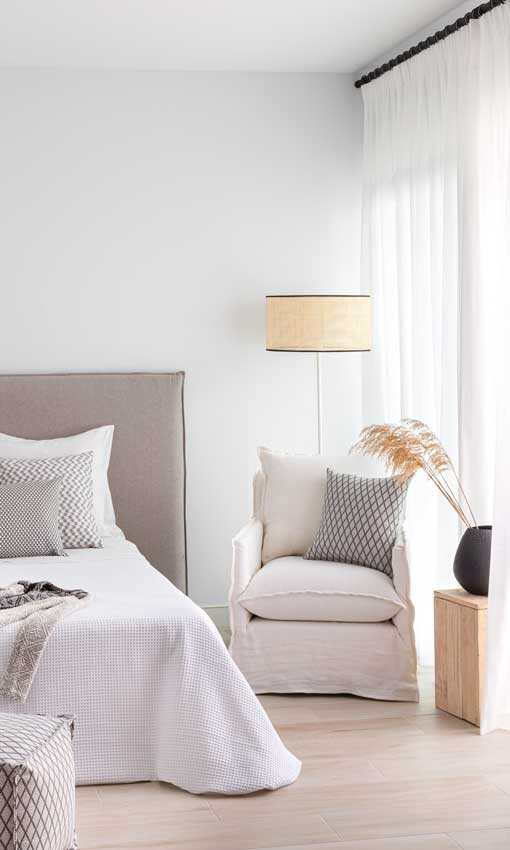 Dormitorio con rincón de lectura, con visillos blancos y barra de cortinas negra
