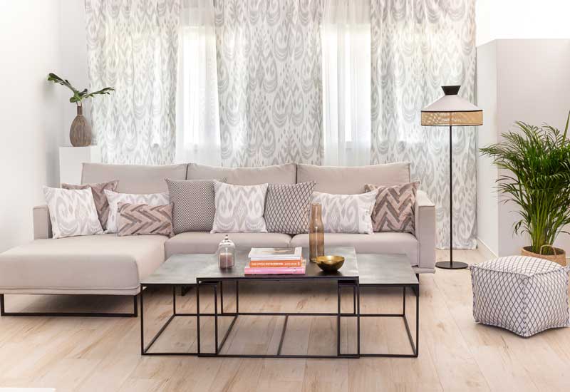 Salón con sofá en beis y cortinas grises con visillos 
