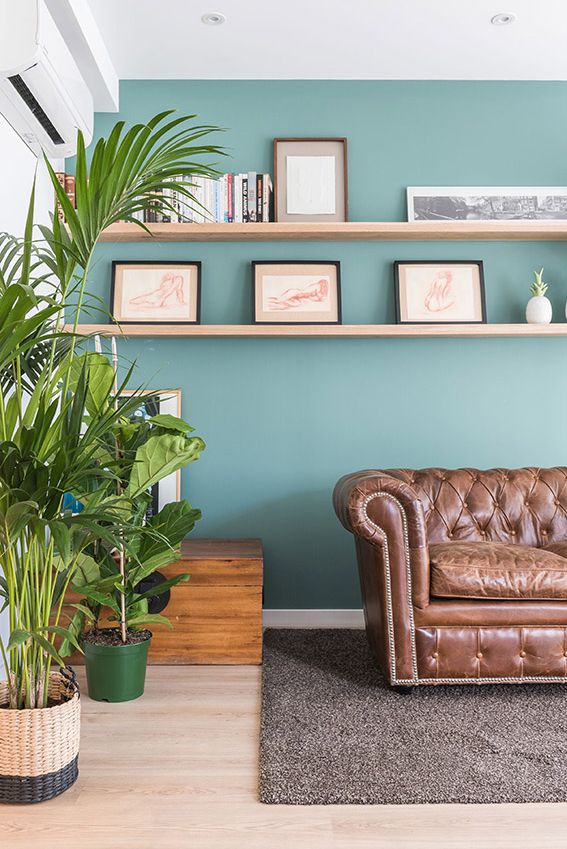 Salón con paredes pintadas de color verde claro y sofá de cuero.