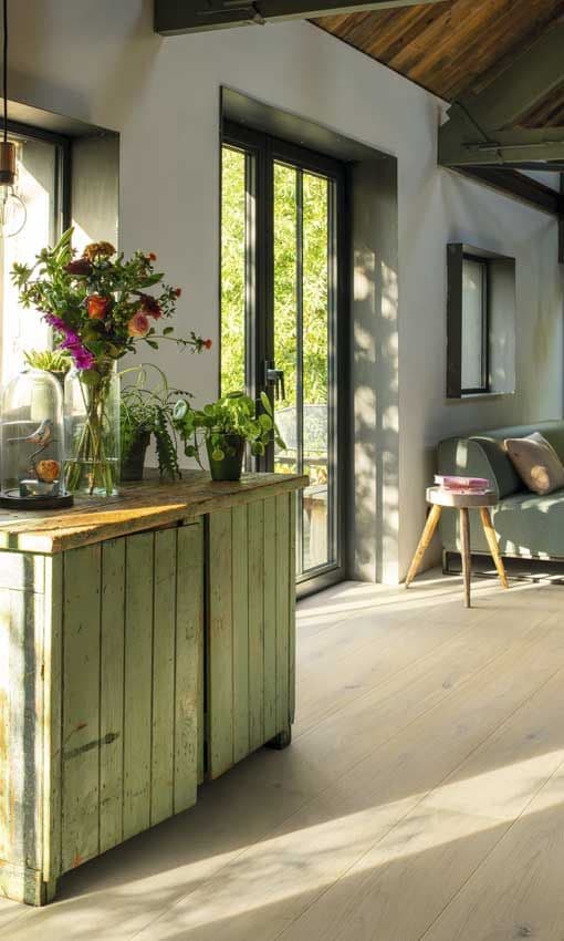 Salón con aire campestre con aparador de madera en verde con jarrón con flores