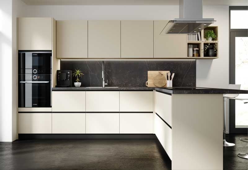 Cocina con muebles blancos, encimera gris y horno y microondas negros en columna