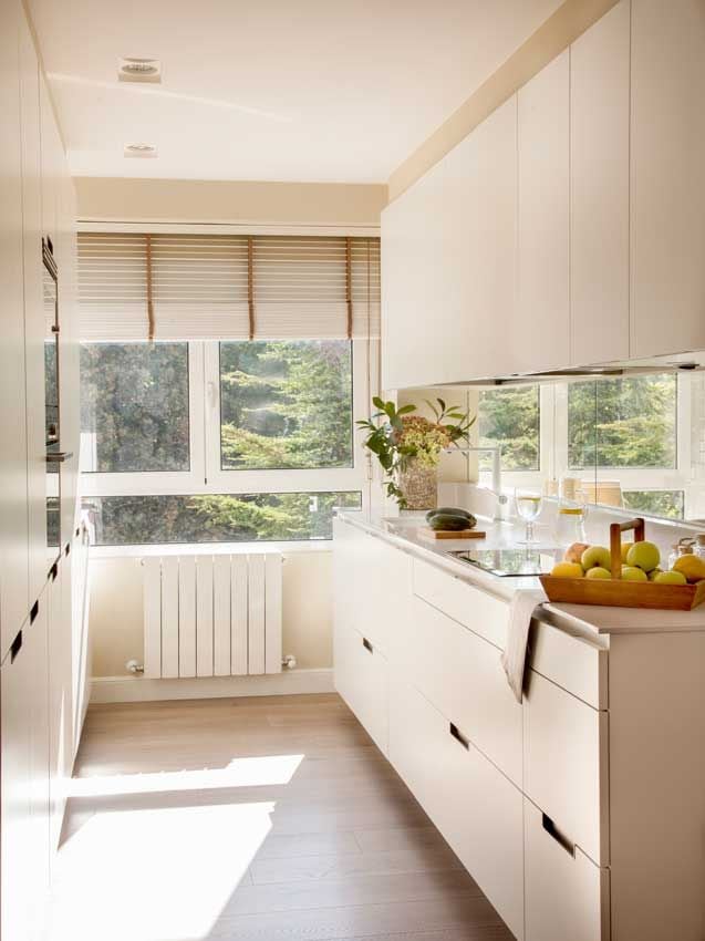 Cocina con muebles en blanco y espejo en la zona del sapicadero