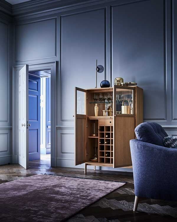 Salón con paredes y puertas de color morado y mueble bar de madera con botellero