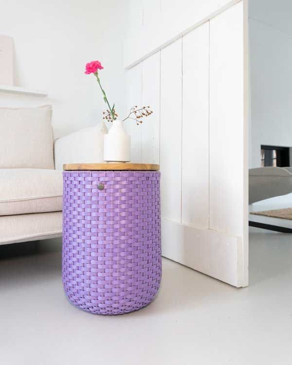 Mesita de plástico reciclado de color morado con tapa de madera y jarrón con flor