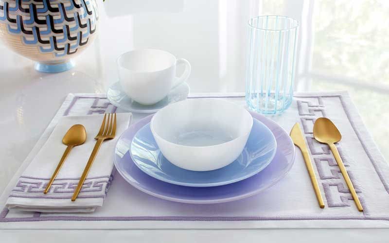 Servicio de mesa con cubiertos dorados y mantel y platos de color morado