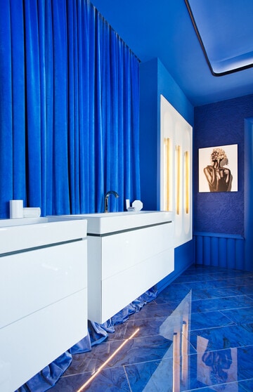 Dos lavabos con sus bajolavabos suspendidos, todo en blanco, envuelto de azul en una intensa tonalidad Klein