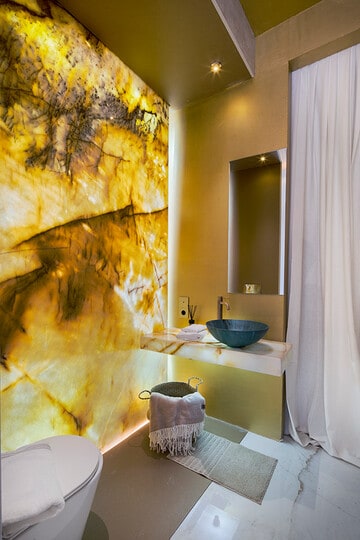 Aspecto pétreo para las paredes de este elegante baño propuesto por Estudio Muher