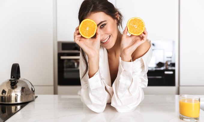 Chica sonriendo con naranja 