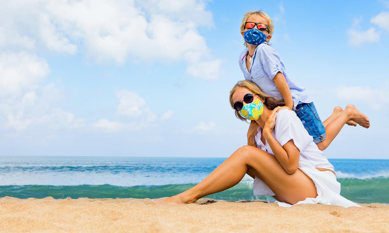 madre e hijo con mascarilla en la playa