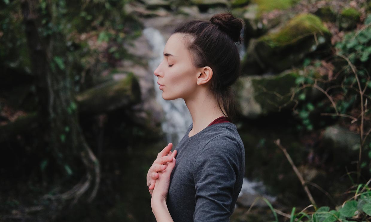 Mujer haciendo ejercicio de respiración en medio de la naturaleza