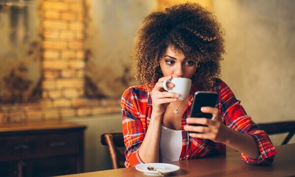 mujer tomando un café y mirando el móvil