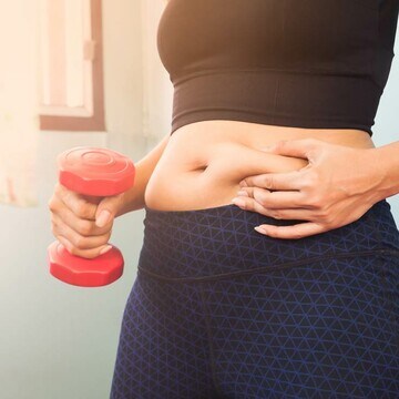 mujer tocando la grasa de su abdomen