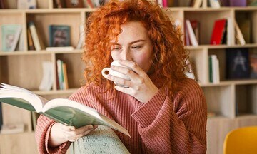 Mujer jovenleyendo un libro mientras toma una taza de café