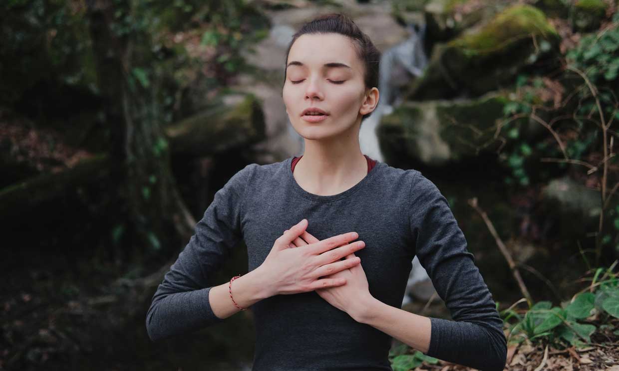 Mujer joven haciendo un ejercicio de respiración estimulando la glándula timo