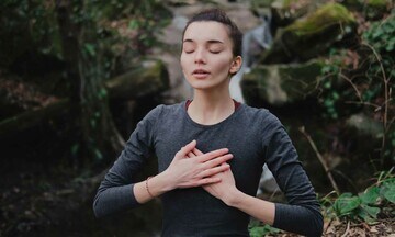Mujer joven haciendo un ejercicio de respiración estimulando la glándula timo