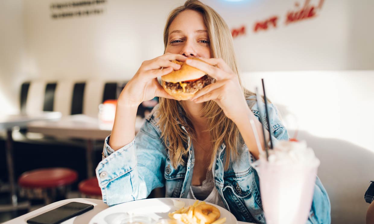 mujer comiendo una hamburguesa