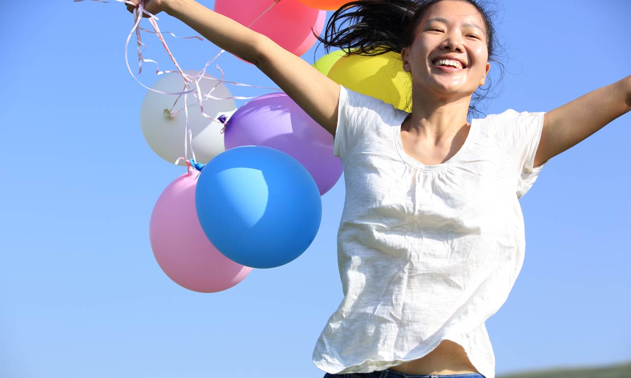 Chica corriendo con unos globos