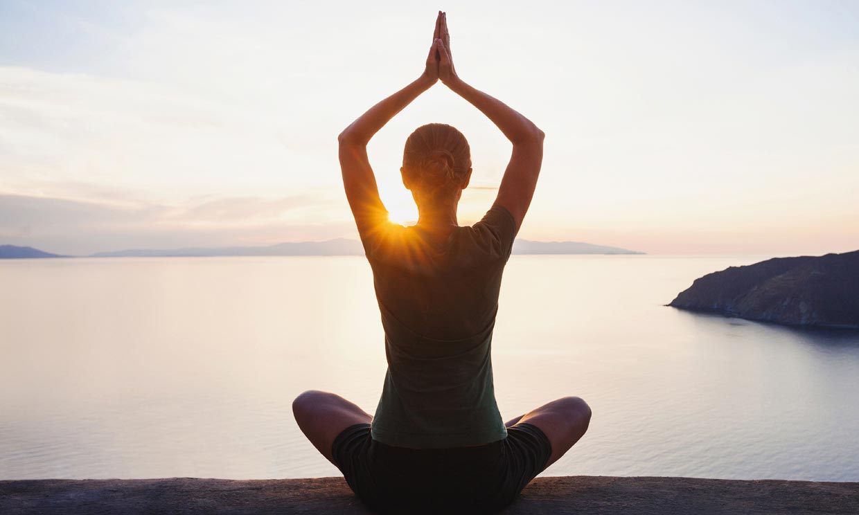 mujer haciendo yoga al amanecer