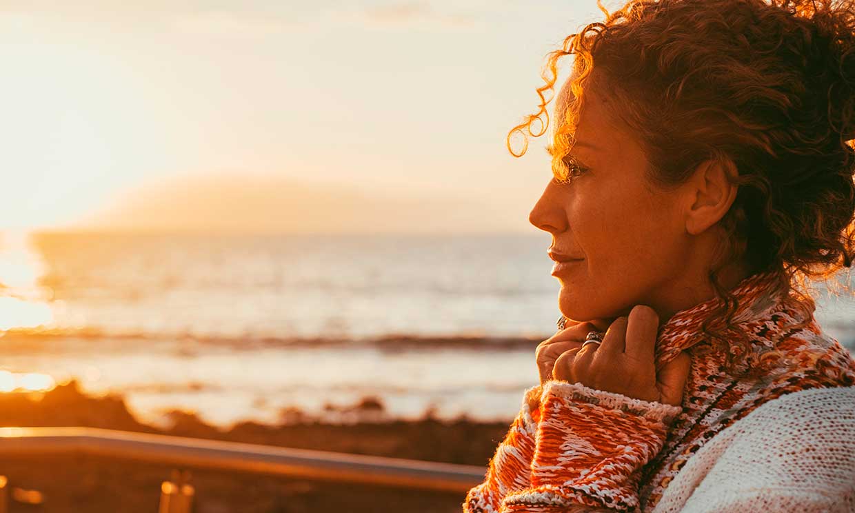 Mujer contemplando la puesta de sol serena y en actitud reflexiva