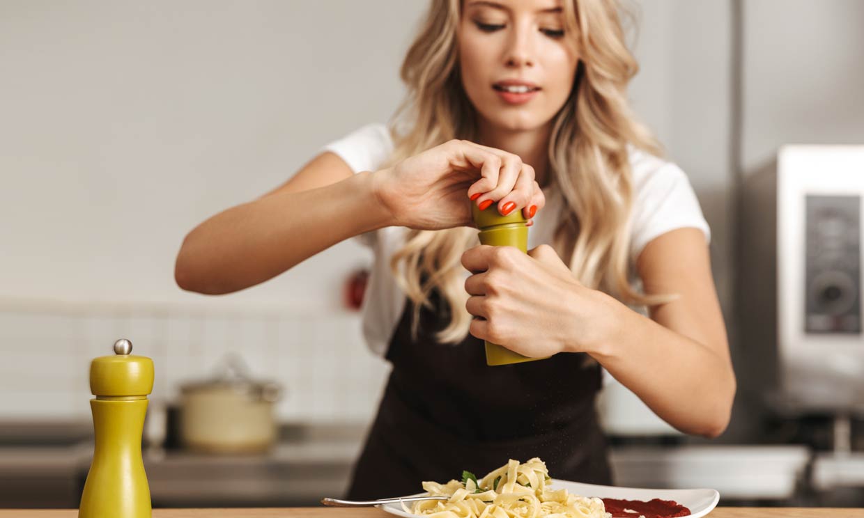 mujer usando pimienta en la cocina