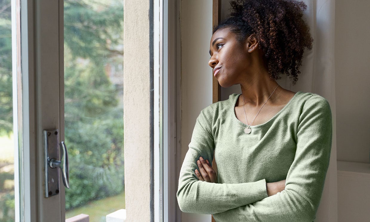 Mujer joven pensativa mirando por la ventana