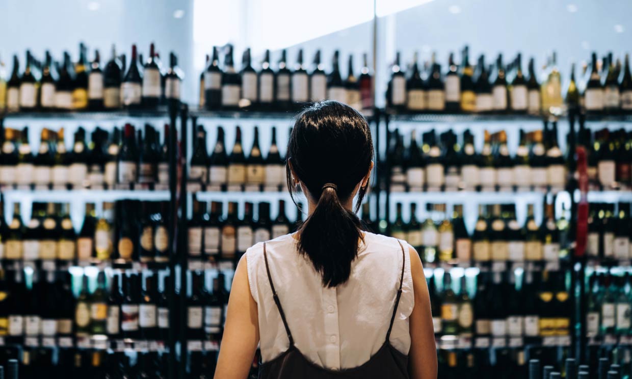 Mujer mirando botellas de vino 