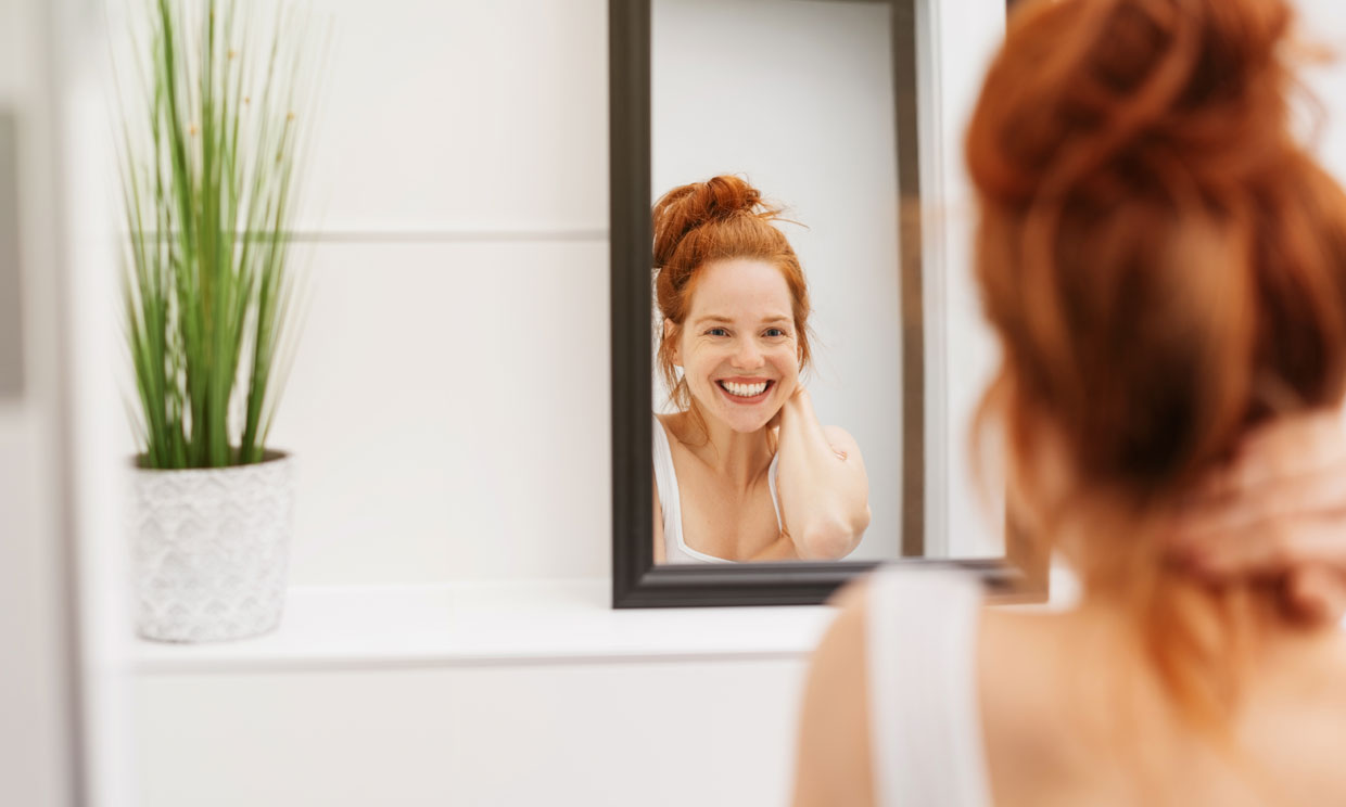 mujer sonriendo frente al espejo