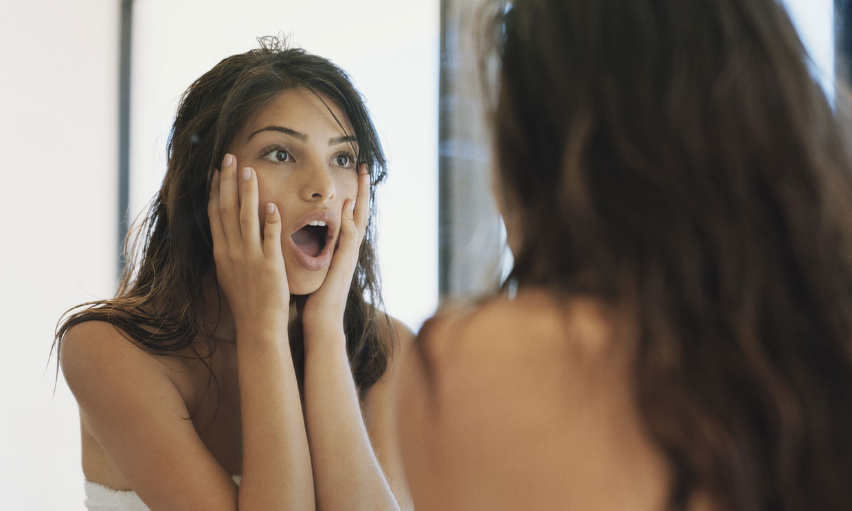 Mujer mirándose al espejo sorprendida