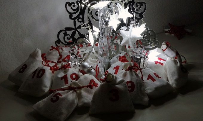 Árbol de Navidad iluminado con saquitos con los días del mes de diciembre debajo