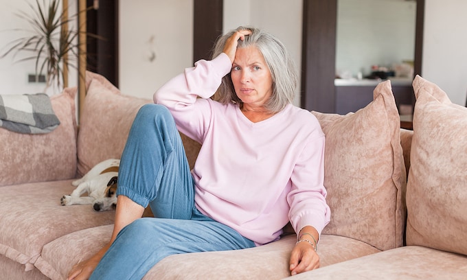 Mujer de 50 años sentada en un sofá en actitud preocupada