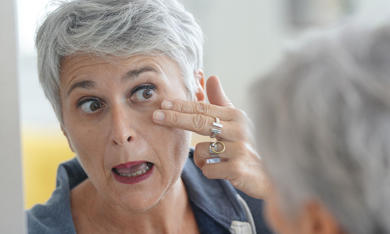 Mujer mirándose al espejo y comprobando las arrugas de su rostro