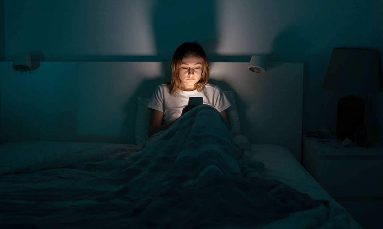 mujer con el móvil en la cama