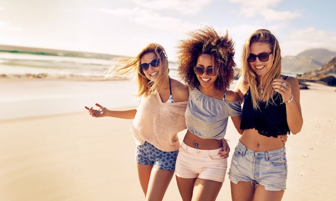 Un grupo de amigas disfrutan paseando juntas por la playa