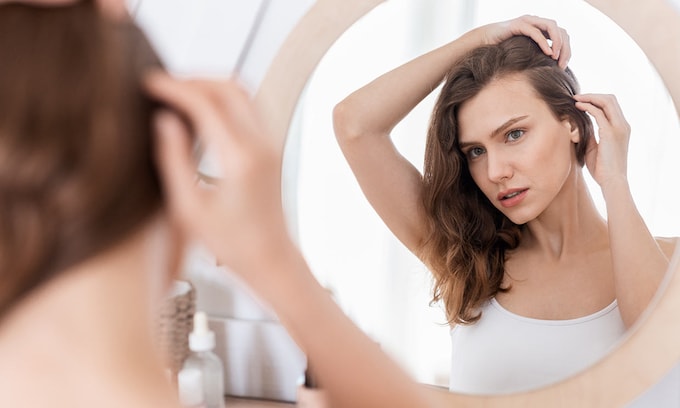 mujer mirando su pelo en el espejo
