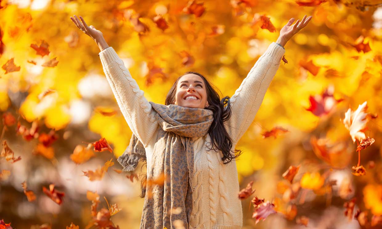 mujer jugando con las hojas de otoño