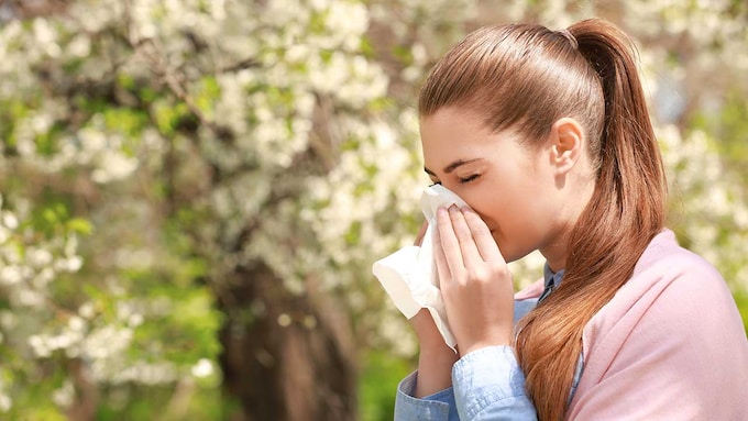 Mujer con un pañuelo estornudando por los efectos de la alergia