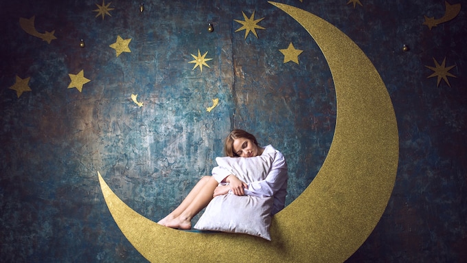 mujer sentada con una almohada en una luna dorada