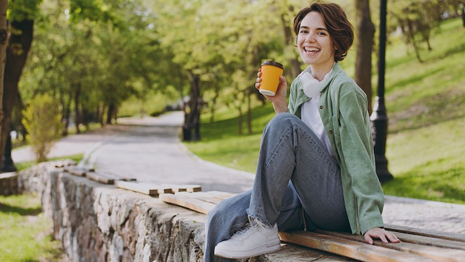 mujer tomando un café al aire libre muy sonriente