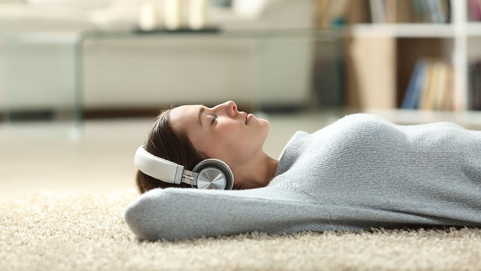 mujer con auriculares tumbada en la alfombra
