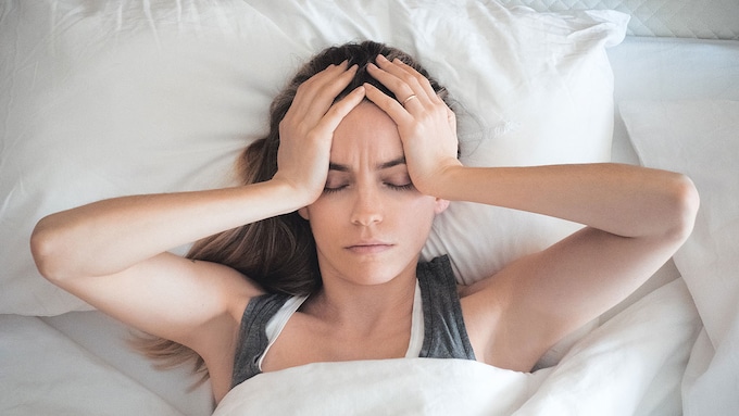 mujer en la cama con dolor de cabeza