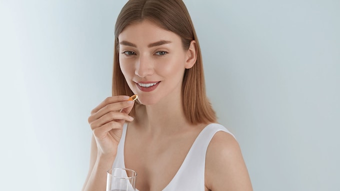 mujer tomando una pastilla con un vaso de agua