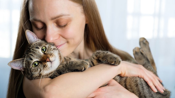 Mujer con un gato en brazos en actitud cariñosa