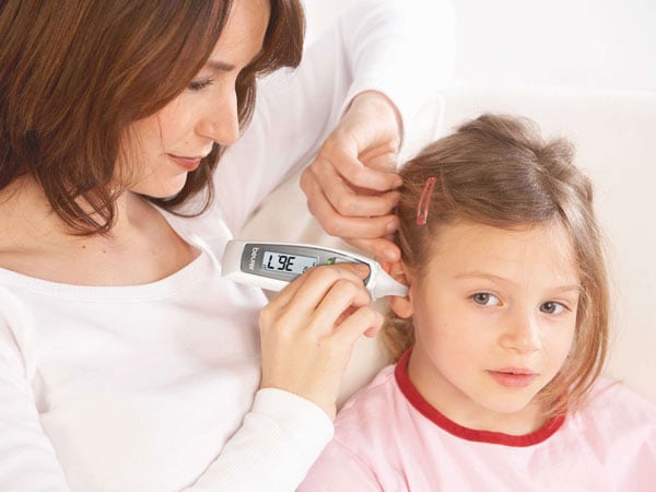 Madre tomando la temperatura a su hija con un termómetro digital de Beurer