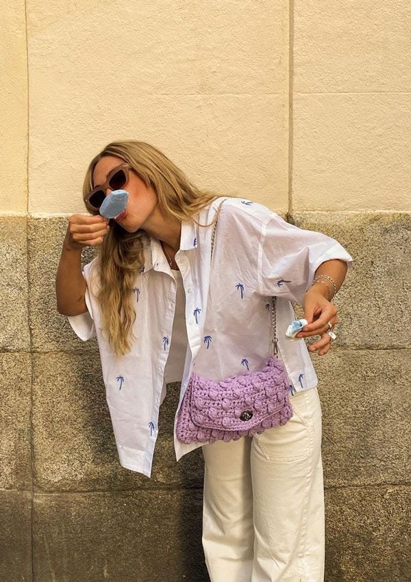 Carlota Weber con pantalón beis, camisa y bolso violeta comiendo un helado