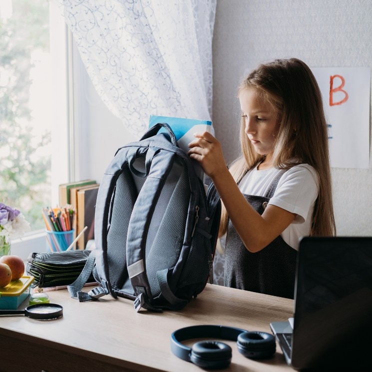 Niña poniendo una libreta dentro de su mochila