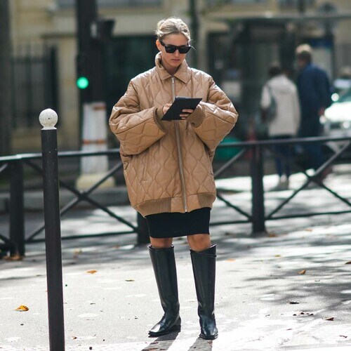 Mujer con abrigo acolchado y tablet en la calle