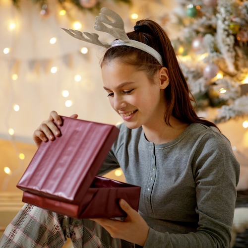 Adolescente abriendo un regalo de Navidad