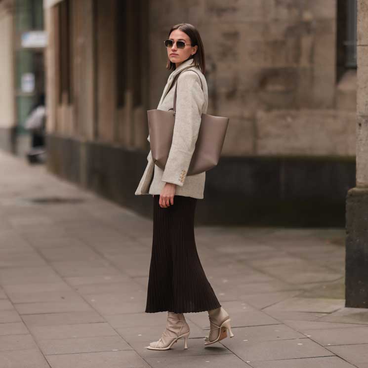 Marie Danker con falda plisada, americana, sandalias y bolso shopper