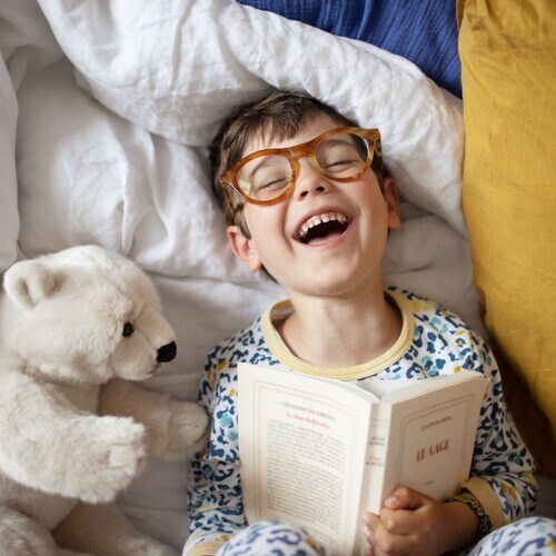 Niño leyendo un libro en la cama 